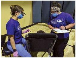 Photo of dental assistant Lizz Rodriguez and Dr. Alyssa Gruba talking to a participant during a screening